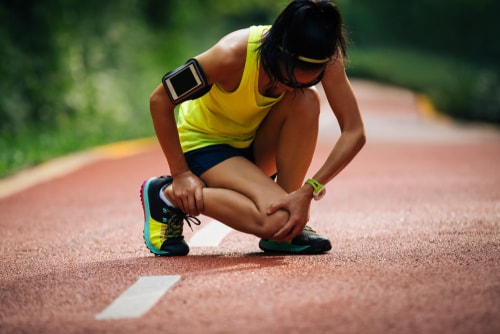 Woman holding sore leg and knee after jogging