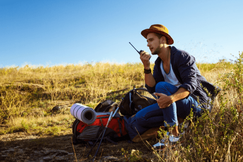 Man with walkie-talkie and heavy sack on a hike