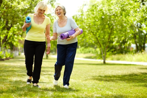Senior women walking in park with yoga mats
